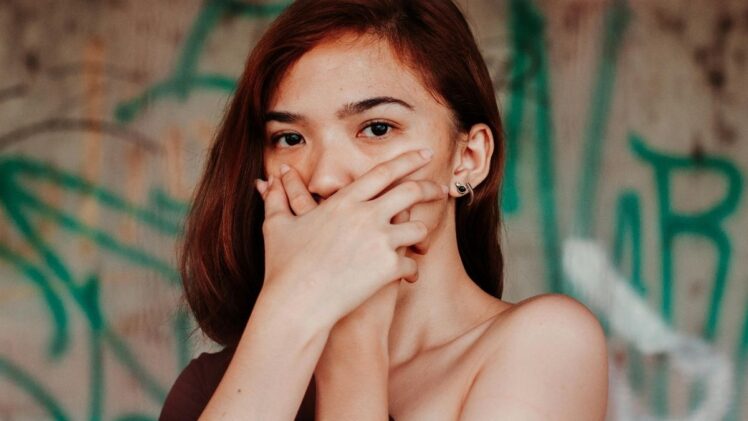 Woman with hands over her mouth.