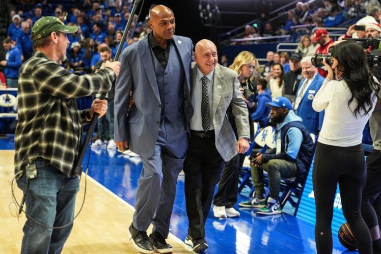 Charles Barkley helps Dick Vitale to their courtside seats for announcing duties.