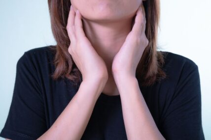 A person feeling the front of their neck.
